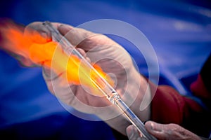 Close-up of the hands of a glassblower working on a glass object.