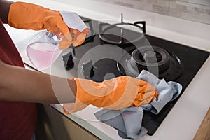 Close up hands with gloves cleaning the stove