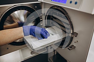 Close-up hands with gloves in the places medical autoclave for sterilising surgical