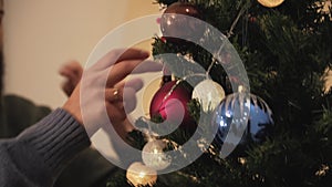 Close-up hands of happy couple decorating the Christmas tree in the room before holiday. New Year and Christmas time