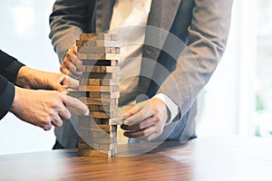 Close up of hands helping build a building of wooden pieces.