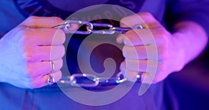 Close-up hands holding chain tight in flashing blue red lights, police flasher