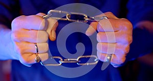 Close-up hands holding chain tight in flashing blue red lights, police flasher