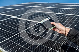 close-up of hands holding euro money in wallet over solar panels on their background.