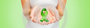 Close up of hands holding green awareness ribbon