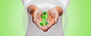 Close up of hands holding green awareness ribbon