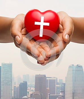 Close up of hands holding heart with cross symbol