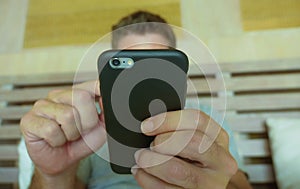 Close up hands holding mobile phone of young man at home bedroom using internet social media app on smartphone networking and text