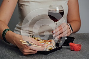 Close-up of hands holding sushi roll with chopsticks.