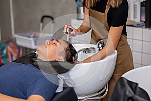 Close up hands inject water to wash Asian man hair after finish process of haircare in beauty salon shop photo