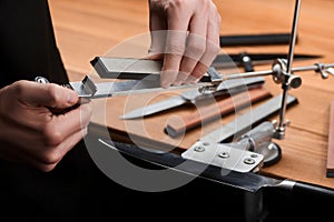 Close-up on hands inserting a whetstone into a manual sharpener machine