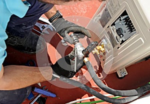 Close-up of the hands of an installer technician joining the copper pipes with a special tool for the assembly of a new air condit