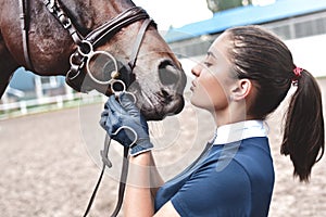 Close up hands of jockey woman hugging a horse. Young girl petting her horse in stable. Equine therapy concept. Love between