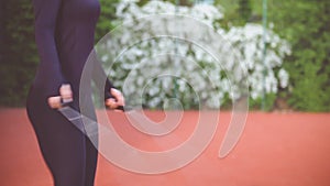 Close-up of hands an jumping women on the jump rope. Outdoor sports. Girl jumping on a skipping rope on on athletic field Flower