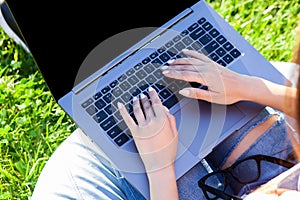 Close up hands on keyboard. Woman working on laptop pc computer with blank black empty screen to copy space in park on
