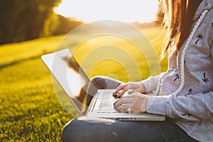 Close up hands on keyboard. Woman working on laptop pc computer with blank black empty screen to copy space in park on