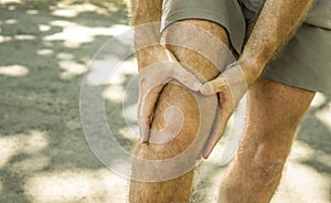 Close up hands and legs of sport man injured touching his knee in pain suffering physical problem or some injury during running