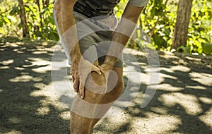 Close up hands and legs of sport man injured touching his knee in pain suffering physical problem or some injury during running