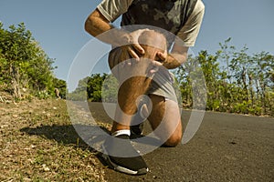 Close up hands and legs of sport man injured touching his knee in pain suffering physical problem or some injury during running