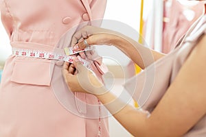 Close up hands Lifestyle Stylish tailor taking measurements on mannequin in studio.