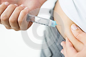 Close up of hands making injection by insulin pen