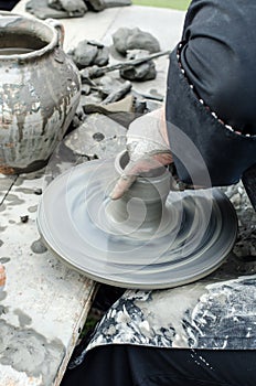 Close-up of hands making pottery from clay on a wheel.