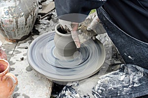 Close-up of hands making pottery from clay on a wheel.