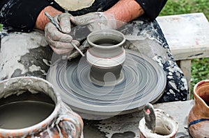 Close-up of hands making pottery from clay on a wheel.