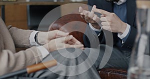 Close-up of hands male and female gesturing while man and woman therapist and client discussing issues in office