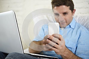 Close up hands of man lying on bed couch using mobile phone and computer working from home