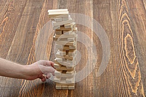 Close-up hands of man pulls out wooden bricks