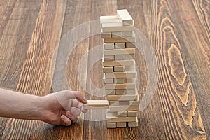 Close-up hands of man pulls out wooden bricks.