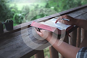 Close up hands of man reading and learning a holy bible in morning on wooden table. christian concept