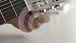 Close-up hands of man spinning tuner knob of acoustic classic guitar for fine tuning to standard key , Music instrumental for jazz