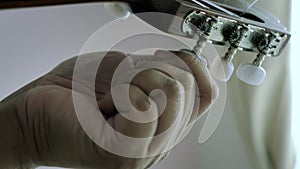 Close-up hands of man spinning tuner knob of acoustic classic guitar for fine tuning to standard key , Music instrumental for jazz