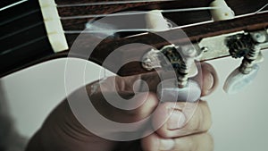 Close-up hands of man spinning tuner knob of acoustic classic guitar for fine tuning to standard key , Music instrumental for jazz