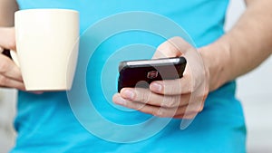 Close-up hands of man texting message on mobile phone.