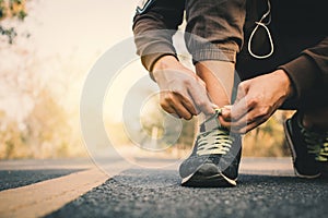 Close-up hands of man tying shoelace during running on the road for health