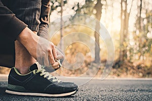 Close-up hands of man tying shoelace during running on the road for health