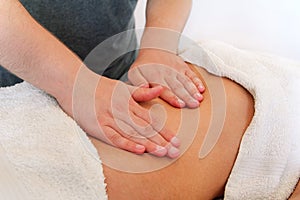 Close up of hands massaging female abdomen