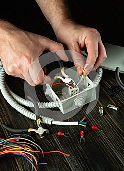 Close-up of the hands of a master electrician during work. Cutting a red wire in a gray junction box. Idea for installation and