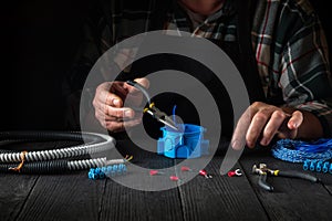 Close-up of hands of a master electrician during work. Installing a cable or wire to blue junction box. Idea for repair of