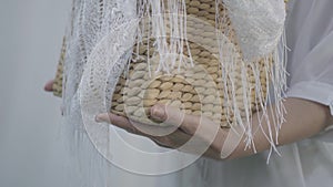 Close-up hands of mature woman holding wicker basket while hanging white clothes on a clothesline outdoors. Washday