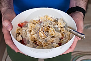 Close-up hands men hold a bowl with pasta salad