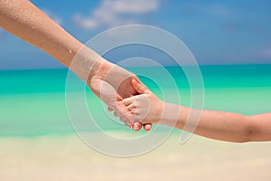 Close-up hands of mother and little kid walking on the beach