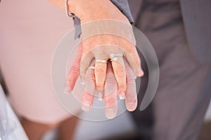 Close up of hands of a newly wed married couple with wedding rings.