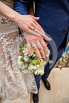 close-up of the hands of the newlyweds on the wedding bouquet.