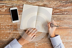 Close up of hands with notebook and smartphone