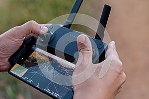 Close-up of hands operating a drone controller with a smartphone display.