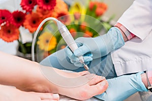Close-up of the hands of a pedicurist wearing surgical gloves wh